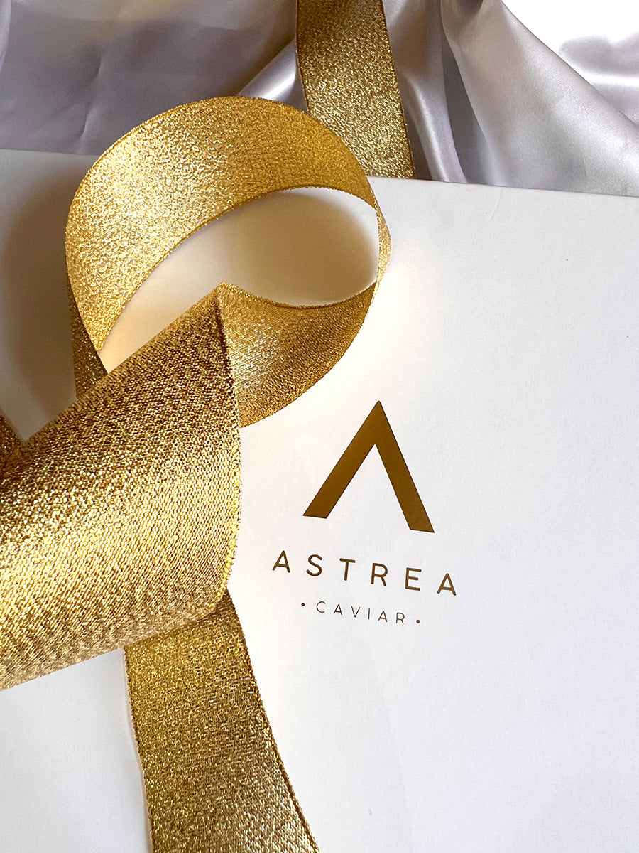 a white box with a gold ribbon that says astrea caviar